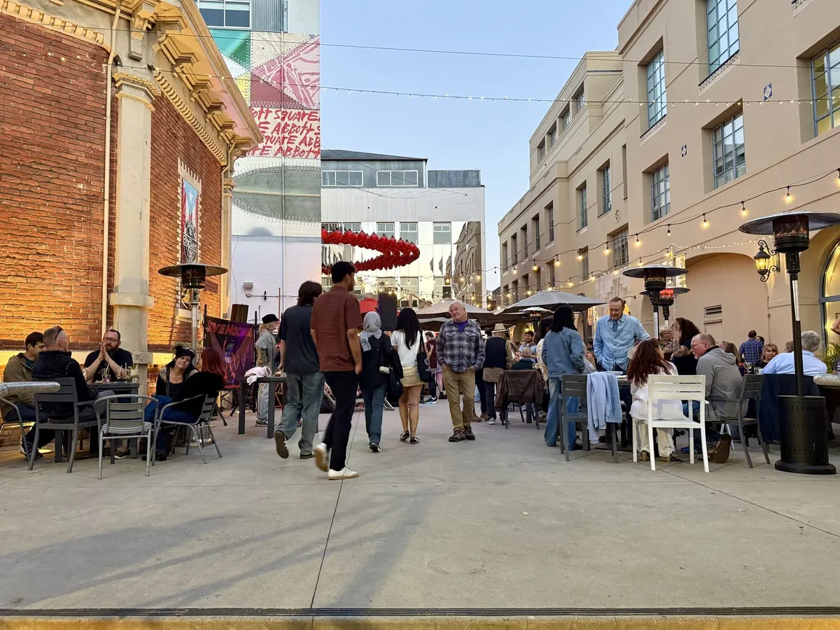 Evening crowd at tables under string lights in Abbott Square