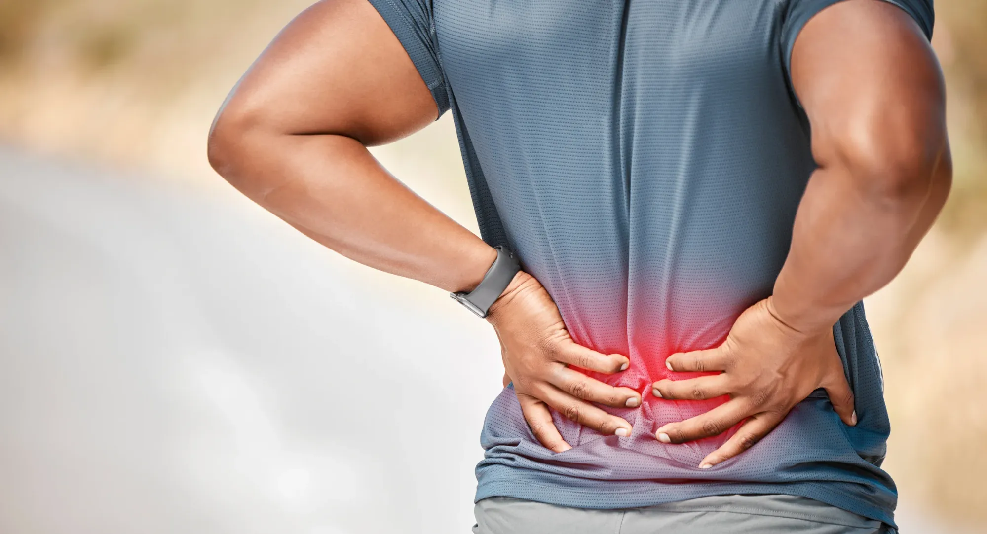 A runner pressing both hands into a painful lower back