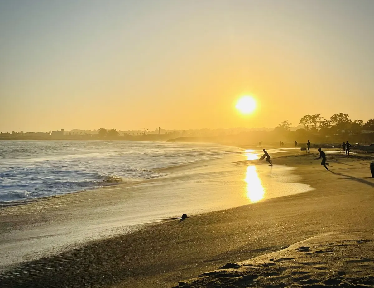 People running on wet sand at the waterline as the sun sets