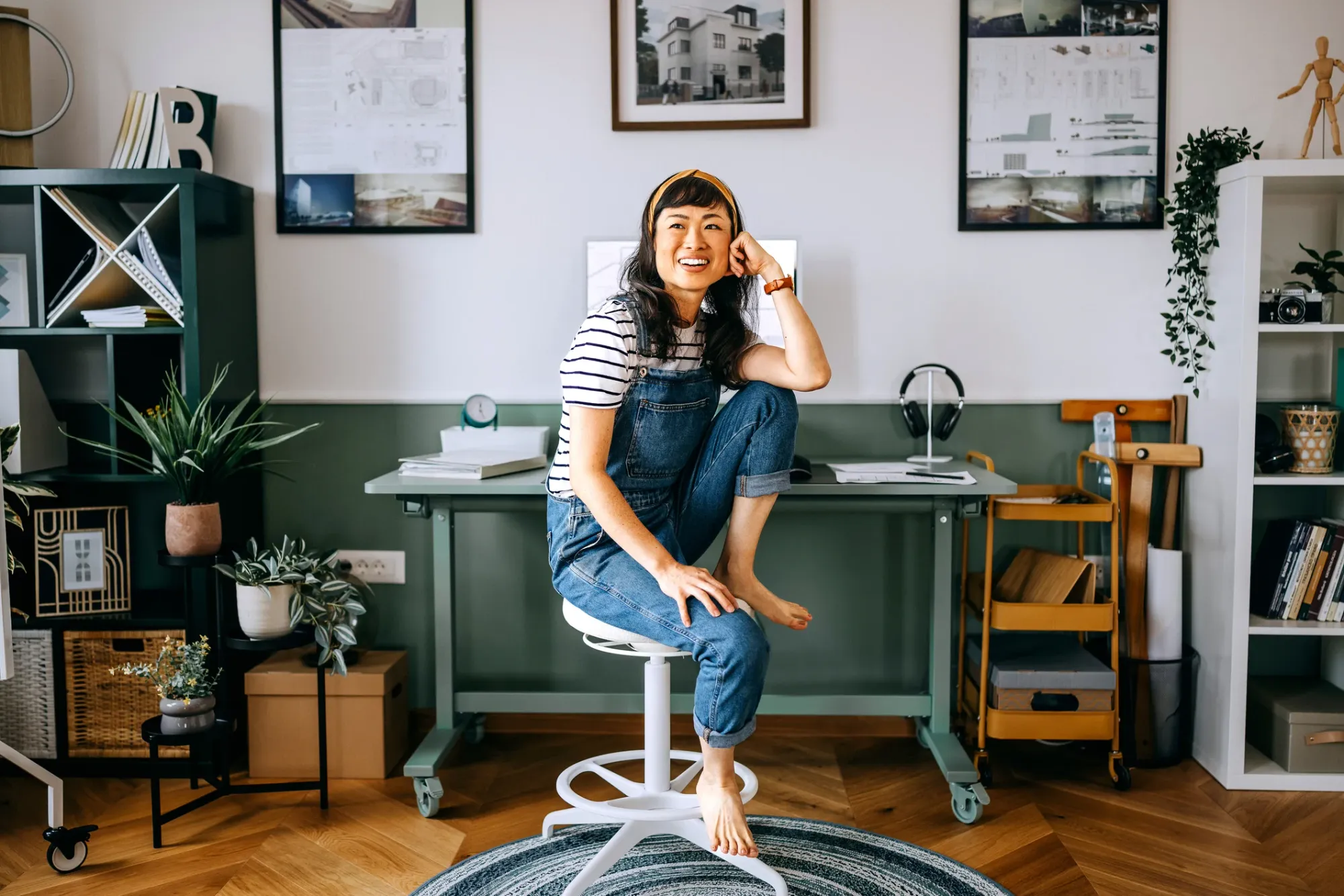 A woman perched on a stool at her home office desk
